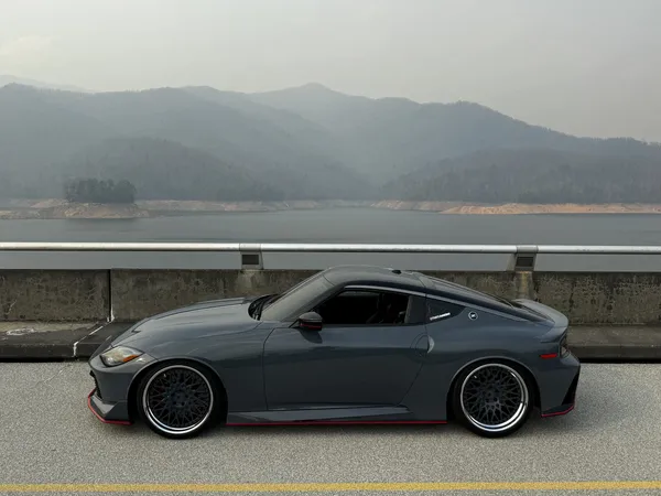 Gray Nissan Z Nismo on Fontana Dam, side view with hazy mountains