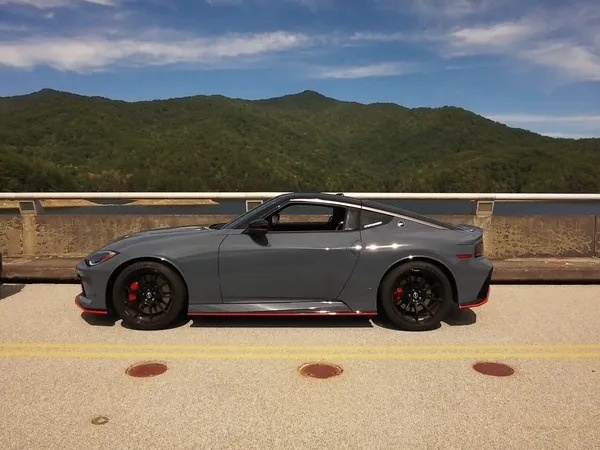 Gray Nissan Z Nismo side profile on Fontana Dam under blue skies